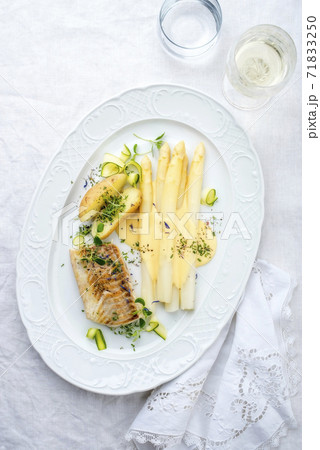 German fried cod fish filet with white asparagus in hollandaise sauce und roast potatoes German fried cod fish filet with white asparagus in hollandaise sauce und roast potatoes 71833250