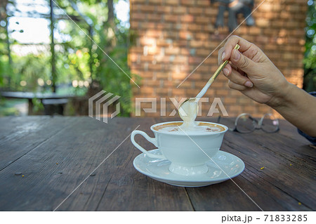 A cups of cappuccino with latte art on wooden table. Beautiful foam, greenery ceramic cups, stylish toning 71833285