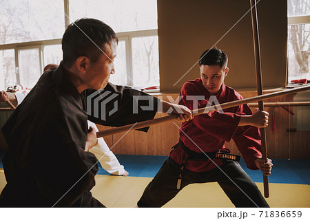 Two men training to fight with sticks.  71836659