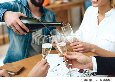 People sit at table and drink champagne together. 71836661