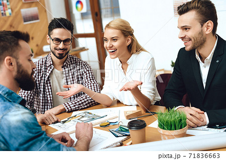 Girl in a blouse speaks with colleagues at table. 71836663