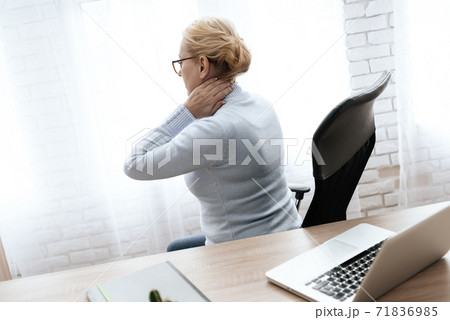 Girl sits at table in an armchair and feels pain. 71836985