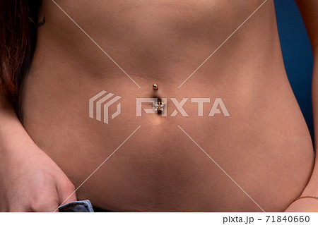 Close-up image of woman's slim belly with piercing 71840660