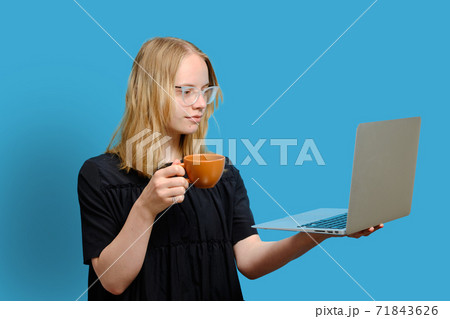 Young cheerful caucasian girl is holding a cup and looking at the 71843626