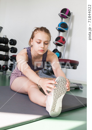 Young girl in a gym does an stretching exercise Young girl in a gym does an stretching exercise 71844022