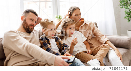 Happy family watching an exciting action-Packed movie on TV together. Happy family watching an exciting action-Packed movie on TV together. 71845171