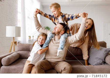 happy family mother father and kids having fun at home on couch . happy family mother father and kids having fun at home on couch . 71845172