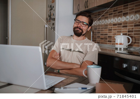 Smiling hipster freelancer holding hands behind head sitting at office desk behind laptop. Smiling hipster freelancer holding hands behind head sitting at office desk behind laptop. 71845401