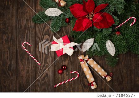 Holiday card - red flower poinsettia, Christmas decorations, gift boxes and candy canes on dark wooden background. Holiday card - red flower poinsettia, Christmas decorations, gift boxes and candy canes on dark wooden background. 71845577