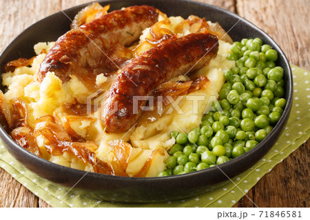 Fried sausages with mashed potatoes, onion gravy and green peas close-up in a plate. horizontal Fried sausages with mashed potatoes, onion gravy and green peas close-up in a plate. horizontal 71846581
