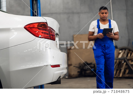 A workshop worker with a clipboard inspects car 71848675
