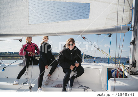 A young guy and two pretty girls set off from the pier on a white sailing yacht for a weekend trip on the lake 71848841