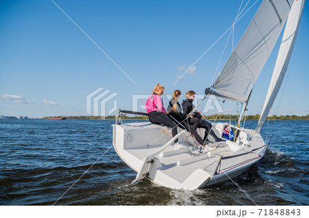 A mixed crew of a sports yacht participates in sailing competitions on the river. One man and two girls. 71848843
