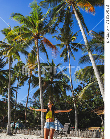 woman streching with palm trees on white sand beach at Paliton Beach in Siquijor Island, Philippines.  Tropical  summer vacation concept 71850023
