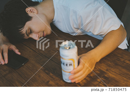 缶ビールを飲んで酔いつぶれる若者 缶ビールを飲んで酔いつぶれる若者 71850475