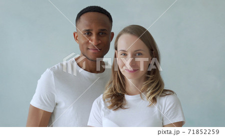 Young interracial couple stand in white t-shirts and smile at the camera 71852259