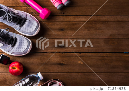 pair sports shoes, apple, jump rope and dumbbell on wood table 71854928