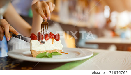 Woman's hands holding a plate with slice of strawberry cheesecake. Girl hands cut the cake by fork. Woman's hands holding a plate with slice of strawberry cheesecake. Girl hands cut the cake by fork. 71856762