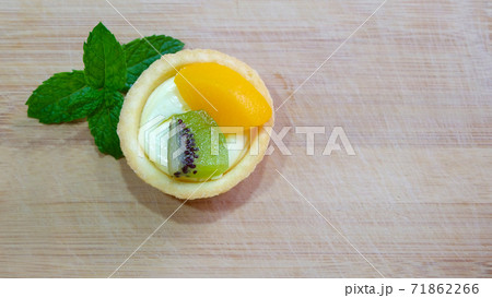 A single mini fruit tart with topping of kiwi and peach slices. 71862266