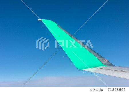 飛行機の窓からの青空とウィングレットの写真素材
