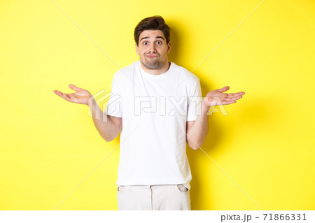 Clueless man shrugging, spread hands sideways confused, dont know anything, standing over yellow background Clueless man shrugging, spread hands sideways confused, dont know anything, standing over yellow background 71866331