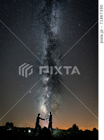 Two persons shaking hands against milky way 71867390