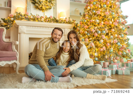 Smiling happy family sitting on the floor near christmas tree 71869248