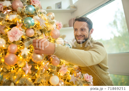 Bearded handsome man decorating new year tree Bearded handsome man decorating new year tree 71869251