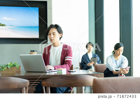 コワーキングスペースでパソコン作業をする若い男性 71872433