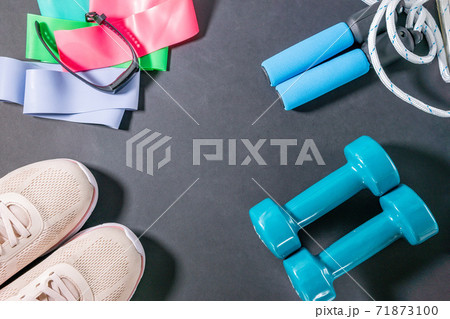 fitness sneakers, fitness bracelet, jump rope, dumbbells, elastic expander at the ankles. Lifestyle and health. flat lay. place to copy text fitness sneakers, fitness bracelet, jump rope, dumbbells, elastic expander at the ankles. Lifestyle and health. flat lay. place to copy text 71873100