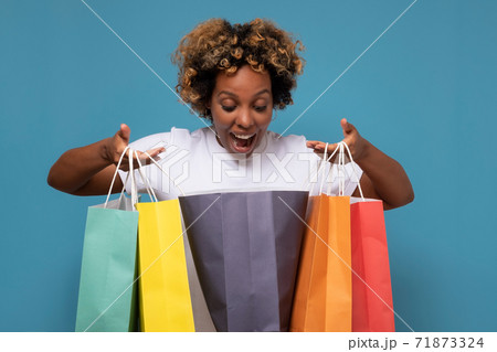 African woman with colorful shopping bags being excited with her purchases. 71873324