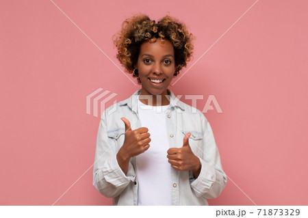 woman with curly hair wearing casual clothes doing happy thumbs up gesture with hand. 71873329