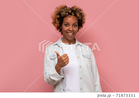 woman with curly hair wearing casual clothes doing happy thumbs up gesture with hand. woman with curly hair wearing casual clothes doing happy thumbs up gesture with hand. 71873331