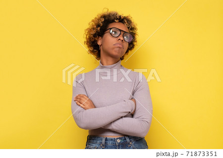 African young woman with curly hair looking with thoughtful and dreamy expression, having some doubts. African young woman with curly hair looking with thoughtful and dreamy expression, having some doubts. 71873351