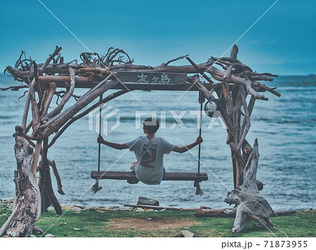 友ヶ島で海を眺めながらブランコを楽しむ友人の写真素材