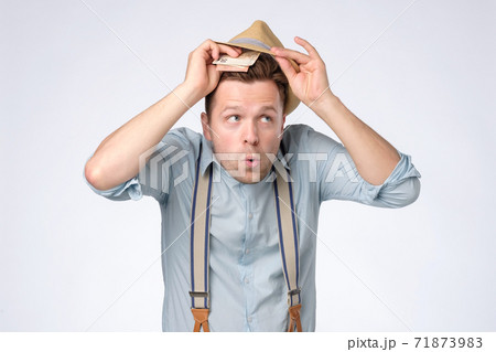 Young greedy man hat hiding money in summer for rainy day. Young greedy man hat hiding money in summer for rainy day. 71873983