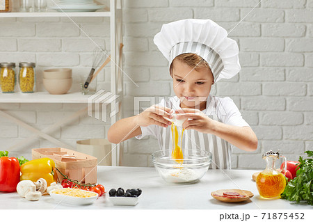 little child boy in chef hat and an apron cooking little child boy in chef hat and an apron cooking 71875452
