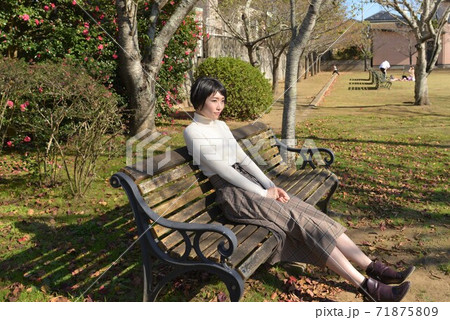 公園のベンチに座る若い女性の写真素材
