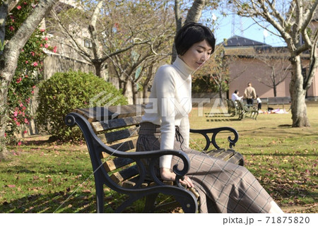 公園のベンチに座る若い女性の写真素材