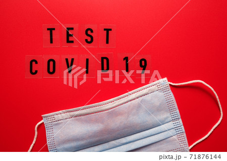 The word COVID test and medical mask on a red background top view. 71876144