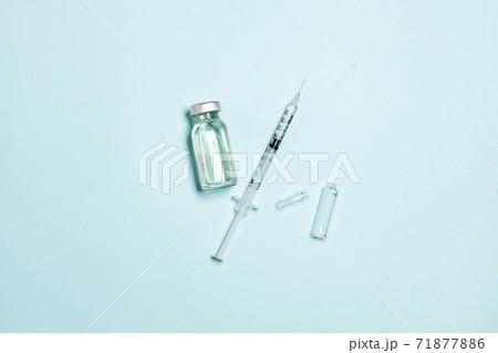 Medical drugs vaccine vial with needle syringe and ampoule on blue background. Coronavirus, influenza or measles vaccination concept 71877886