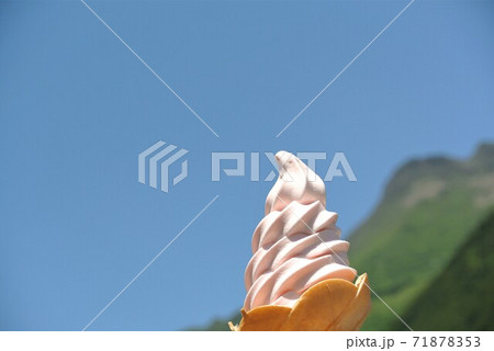 Soft serve (rose flavor) with blue sky and green mountain as background. 71878353