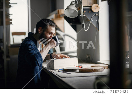 Man in the workshop with a wood Man in the workshop with a wood 71879425
