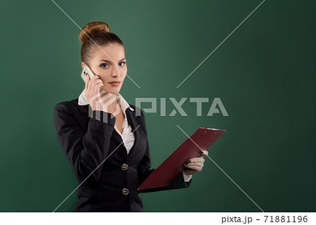 Pretty businesswoman with clipboard talks on phone green background Pretty businesswoman with clipboard talks on phone green background 71881196