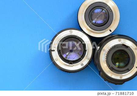 Several photographic lenses lie on a bright blue background. Space for text 71881710