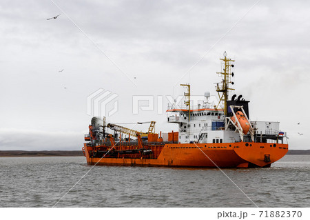 Vessel engaged in dredging. Dredger working at sea. Ship excavating material from a water environment. 71882370