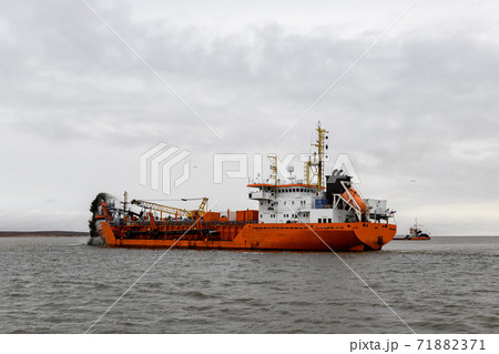 Vessel engaged in dredging. Dredger working at sea. Ship excavating material from a water environment. 71882371