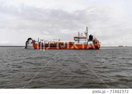 Vessel engaged in dredging. Dredger working at sea. Ship excavating material from a water environment. 71882372