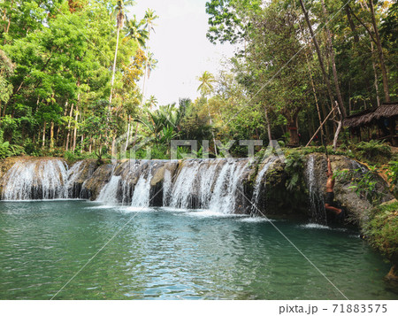 woman swinging with the rope at the pool of waterfalls, Cambugahay Falls on Siquijor Island in Philippines 71883575