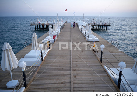 Wooden bridge with sunbeds in the sea at sunset. Wooden bridge with sunbeds in the sea at sunset. 71885020